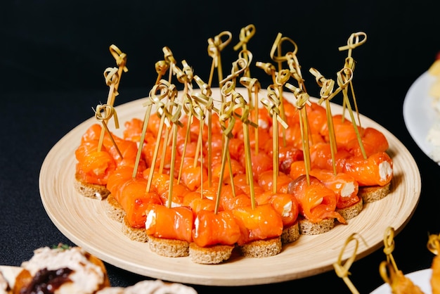 Voorgerecht canapé met gerookte zalm op spiesjes op houten plaat