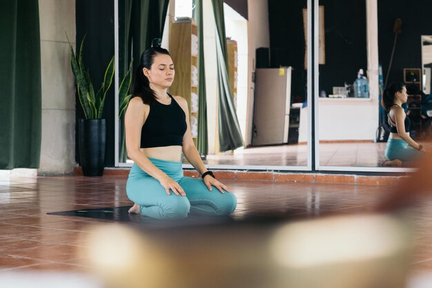 Voorraadbeeld van een vrouw die op de vloer van een yogastudio zit te mediteren