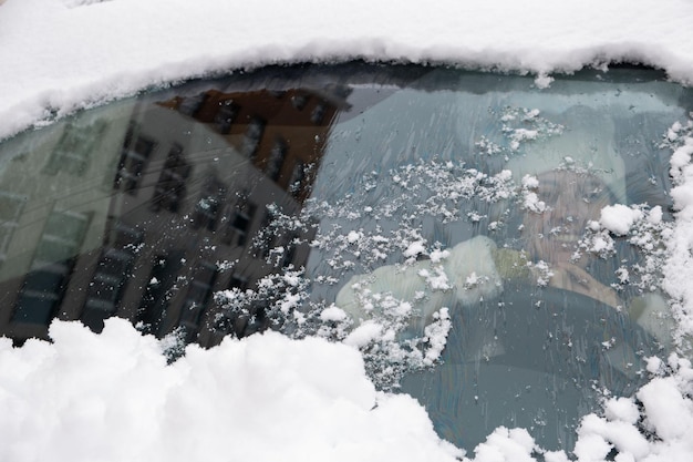 Voorruit bedekt met sneeuw lachende vrouw in auto kopieerruimte