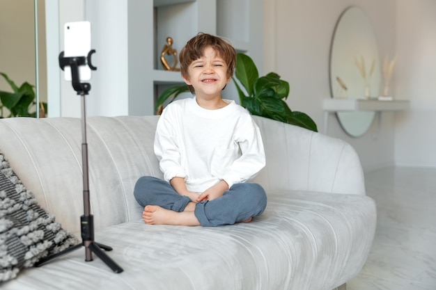 voorschoolse blanke jongen heeft een videogesprek met smartphone op een treepod