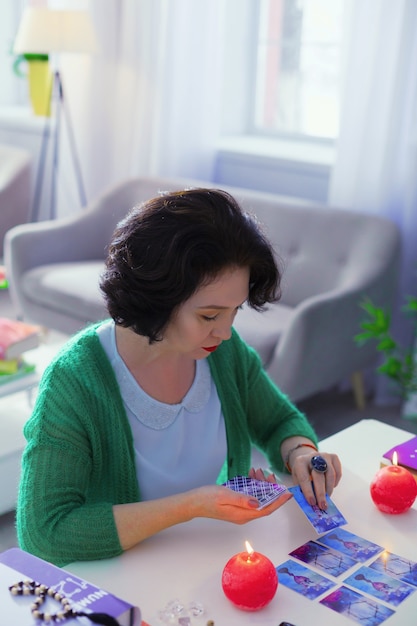 Voorspelling van de toekomst. slimme getalenteerde waarzegster die de tarotkaarten op tafel legt terwijl ze haar werk doet