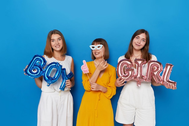 Voorste afbeelding van een drietal gelukkige vrouwen om geslacht te hebben onthult een geïsoleerde blauwe achtergrond