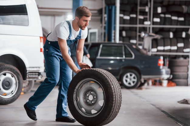 Vooruit gaan. Werknemer in het blauw gekleurde uniform werkt in de autosalon