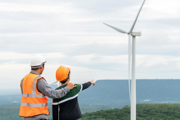 Vooruitstrevende ingenieur met zijn zoon in het windmolenpark boven op de berg