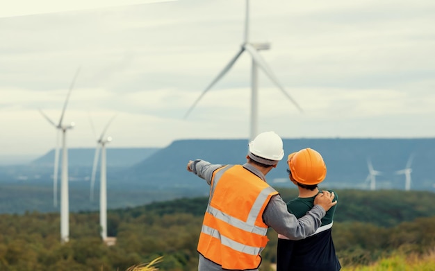 Vooruitstrevende ingenieur met zijn zoon in het windmolenpark boven op de berg