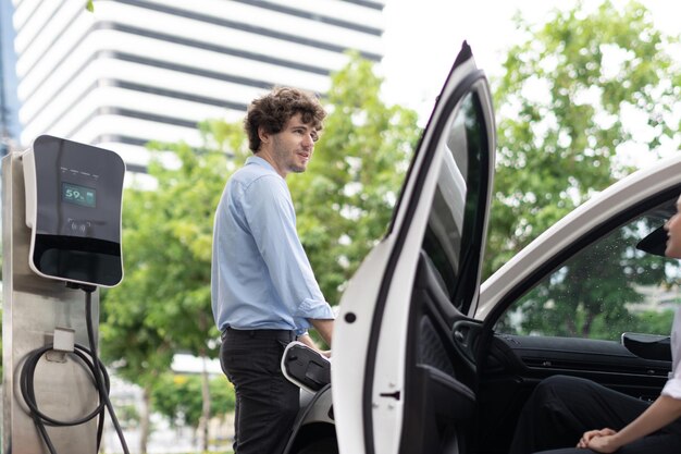 Vooruitstrevende zakenman en zakenvrouw bij oplaadpunt en EV-auto