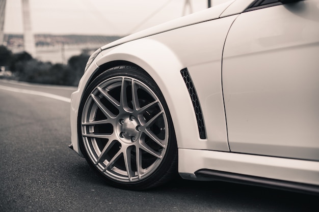 Voorwiel van een witte sedanauto die op de weg wordt geparkeerd