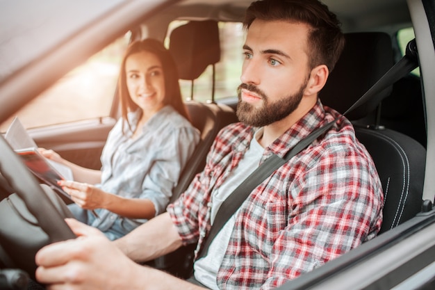 Voorzichtig en aardige vent rijdt auto en kijkt recht vooruit. Hij besteedt al zijn aandacht aan de weg. Meisje zit naast hem.