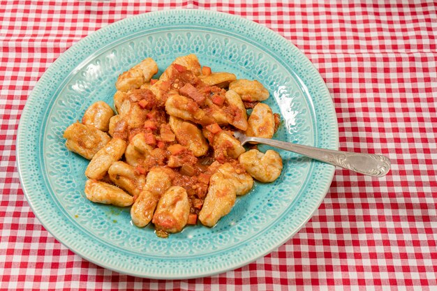 Vork op een bord zelfgemaakte gnocchi met tomatensaus. Italiaans eten.