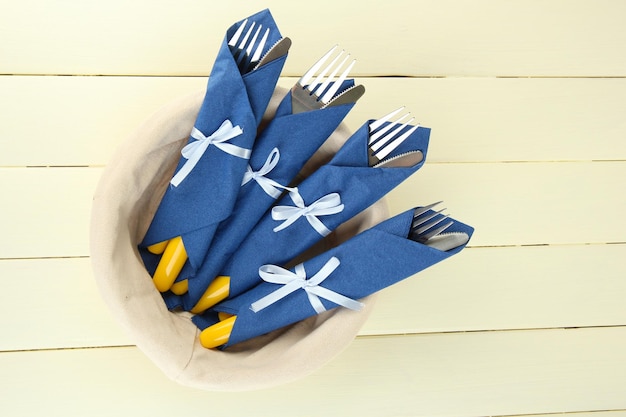 Vorken en messen verpakt in blauwe papieren servetten op een houten achtergrond kleur