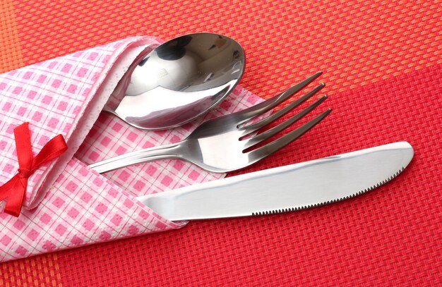 Vorklepel en mes in een geruite doek met een strik op een rood tafelkleed