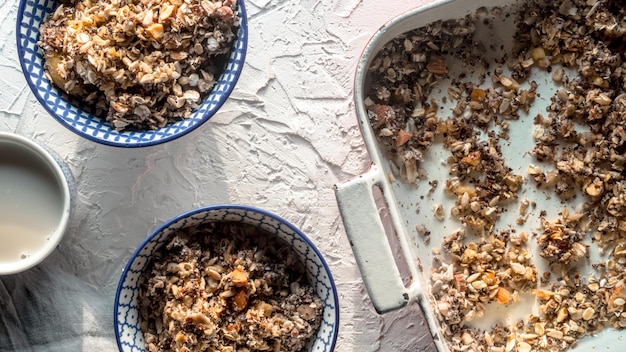 Vorm voor het bakken van kommen met muesli en kokosmelk op een witte achtergrond