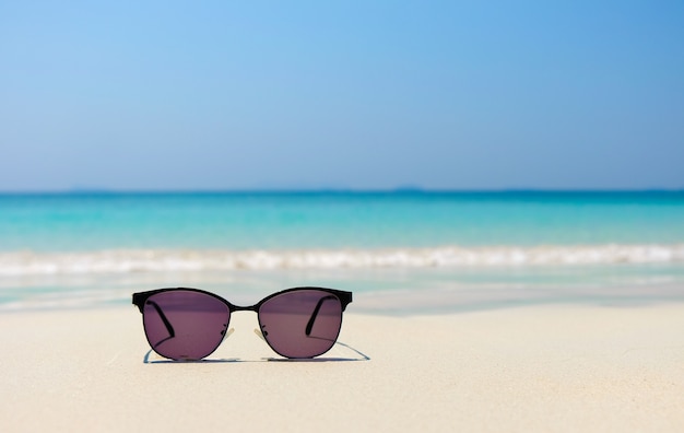 Vorm zonnebril op overzees strand onder duidelijke blauwe hemel. De zomervakantie ontspant achtergrond met exemplaar spac