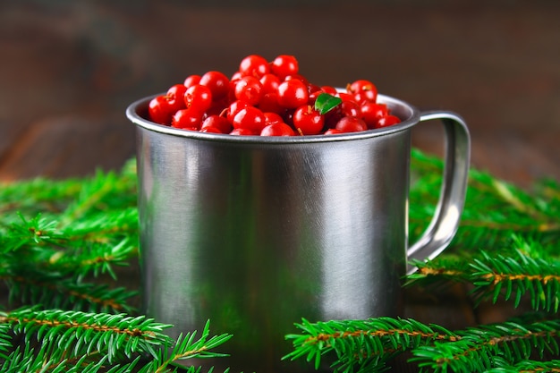 Vossebes, vosbes, cranberry, bosbessensap in een aluminium mok op een bruine houten tafel.