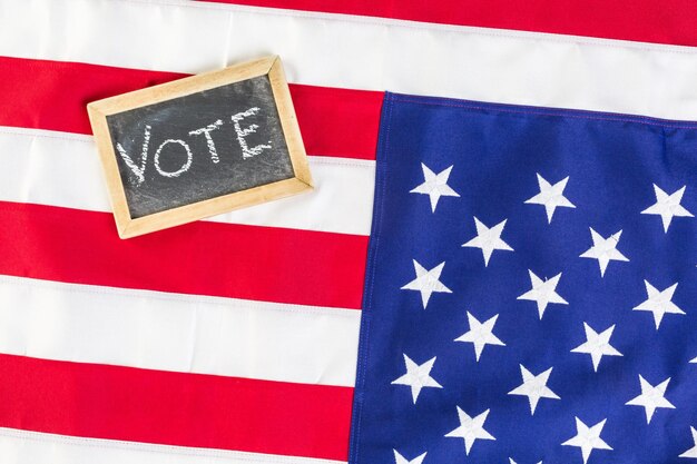 Vote sign on chalk board next to the American Flag.