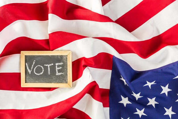 Vote sign on chalk board next to the American Flag.