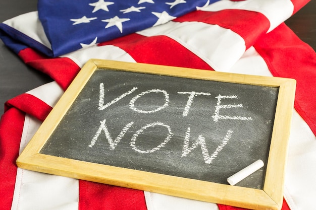 Vote sign on chalk board next to the American Flag.