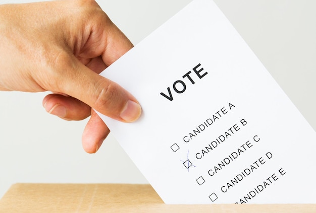 Photo voting, civil rights and people concept - close up of male hand putting vote into ballot box on election