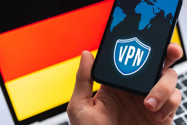 ドイツのVPN安全で安全なインターネットの概念携帯電話とVPNアプリケーションを備えたプライバシーハンド背景写真の旗とラップトップ