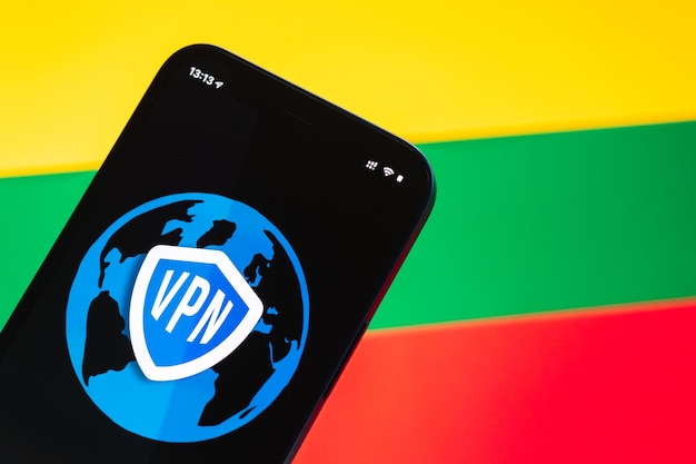 リトアニアのVPN安全で安全なインターネットの概念携帯電話とVPNアプリケーションを備えたプライバシーハンド背景写真にフラグとラップトップ