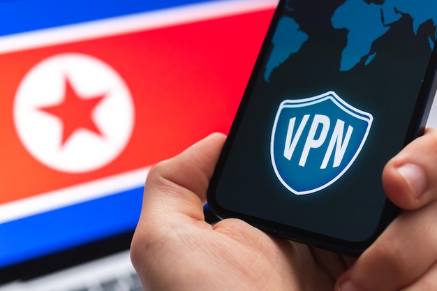 북한의 VPN 안전하고 안전한 인터넷 개념 개인 정보 보호 손 휴대 전화 및 VPN 응용 프로그램 플래그 및 배경에 노트북 사진