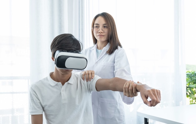 환자 남성이 있는 VR 상자, 손을 뻗어 물리 치료를 하는 여의사, 기술 개념은 마치 의사가 집에서 치료를 받으러 온 듯한 느낌을 도왔습니다.