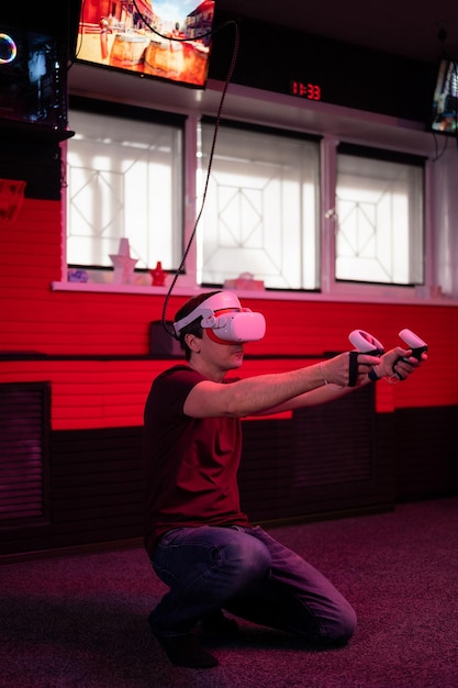 Vr game and virtual reality man gamer fun playing on futuristic\
simulation video shooting game holding in hands joysticks gun in\
entertainment vr room with innovation technology and neon\
light