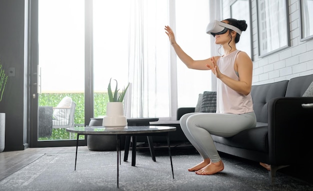 VR metavers en futuristisch met een vrouw in de woonkamer van haar huis die een headset gebruikt om toegang te krijgen tot een 3D-game Technologie virtual reality en gamen met een vrouwelijke gamer die ai gebruikt om games te spelen