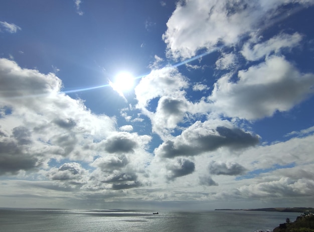 Vrachtschip op de open zee Witte wolken op een blauwe zonnige lucht achtergrond en zee