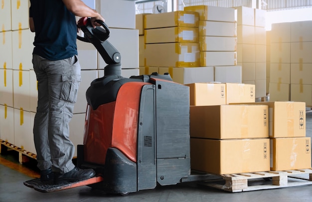 Vrachtverzendingsdozen, Opslag. Werknemer werken met elektrische heftruck pallet jack kartonnen dozen op pallet lossen.