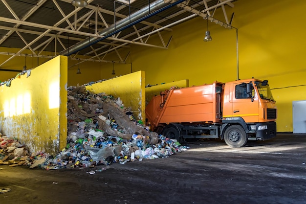 Foto vrachtwagen gooit afval naar het sorteren van moderne afvalverwerkingsfabriek afval scheiden en sorteren van afval recycling en opslag van afval voor verdere verwijdering