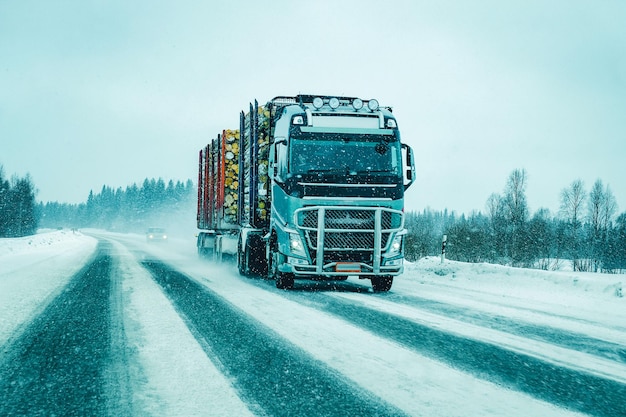 Vrachtwagen in sneeuw winter weg van Finland. Vrachtwagenchauffeur op de snelweg. Vrachtwagen die logistiek werk doet. Oplegger met chauffeur. Grote vrachtauto rijden. Vracht levering. Transport export industrie. Container met goederen