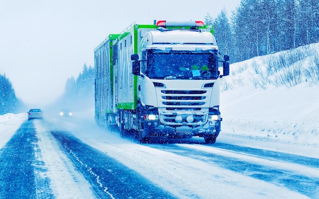 Vrachtwagen in sneeuw winter weg van Finland. Vrachtwagenchauffeur op de snelweg. Vrachtwagen die logistiek werk doet. Oplegger met chauffeur. Grote vrachtauto rijden. Vracht levering. Transport export industrie. Container met goederen