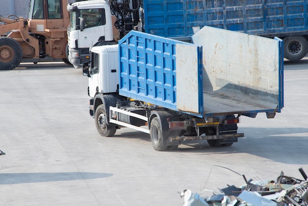 Vrachtwagen met een open laadbak in de buurt van een stapel verfrommeld oud schroot Apparatuur voor het recyclen van metaalafval