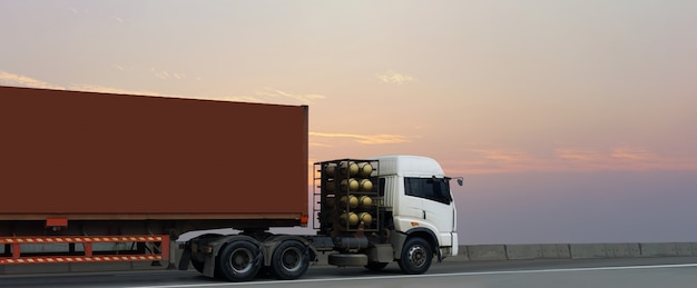 Vrachtwagen op wegweg met rode container, logistische industrieel met zonsopganghemel