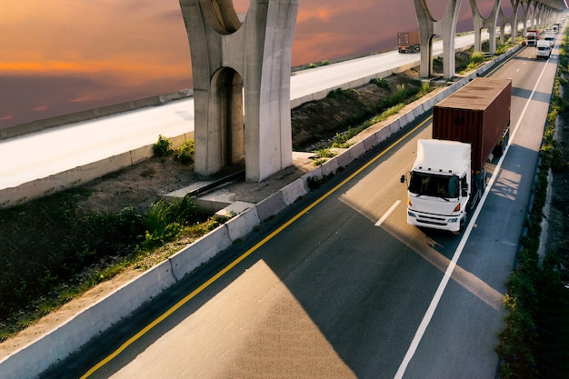 Vrachtwagen op wegweg met rode container, vervoer op de asfaltsnelweg met zonsopganghemel