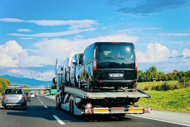 Vrachtwagenvervoerder met minibusjes op de asfaltweg in Slovenië.