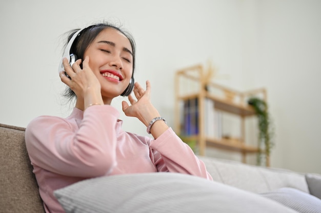 Vreedzame en ontspannen Aziatische vrouw met een koptelefoon met gesloten ogen en genietend van de muziek