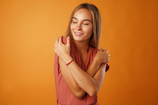 Vreedzame jonge blonde vrouw hand in hand op haar borst.