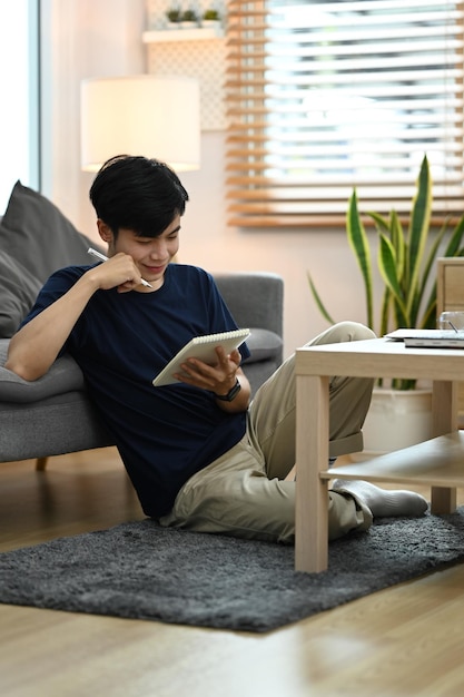 Vreedzame man in vrijetijdskleding die favoriete literatuur leest in een gezellige woonkamer