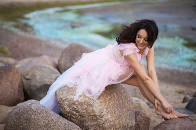 Vreedzame vakantie paradijs vrouw lopen op zonsondergang oceaan strand. Meisje in het roze romantische kleding ontspannen op uitje van de luxe het tropische zomer.