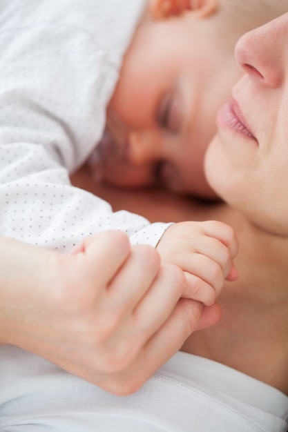 Vreedzame vrouw die met haar baby ligt die een fopspeen zuigt