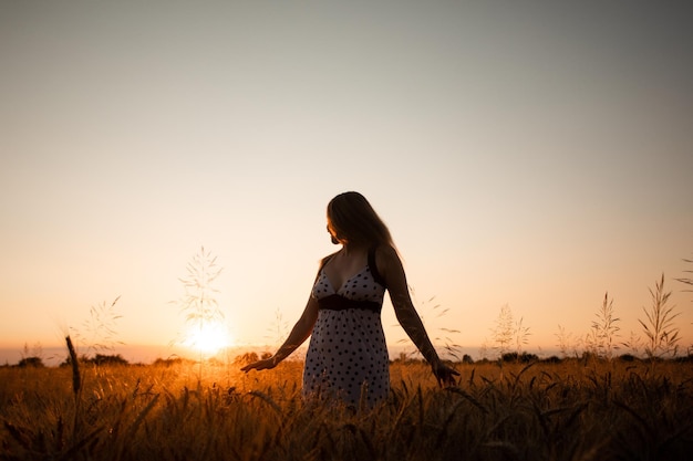 Vreedzame vrouw verwelkomt de rijzende zon in het veld