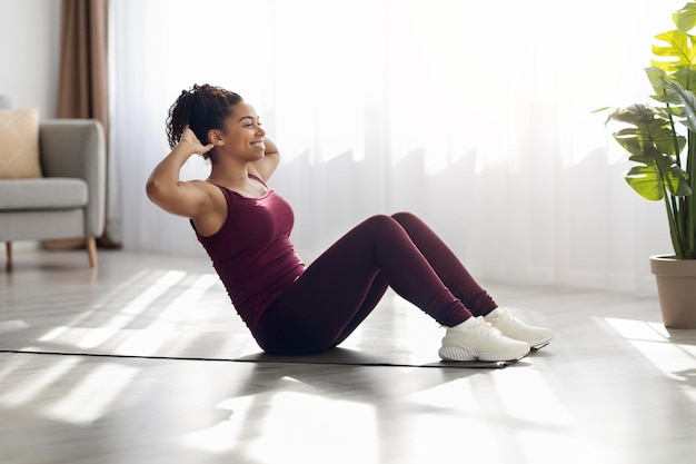 Vreemde Afro-Amerikaanse vrouw oefent thuis op een fitnessmat