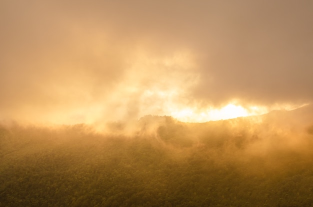 Foto vreemde gouden wolken en mist op bergen, veroorzaakt door het licht van de zon en de storm.