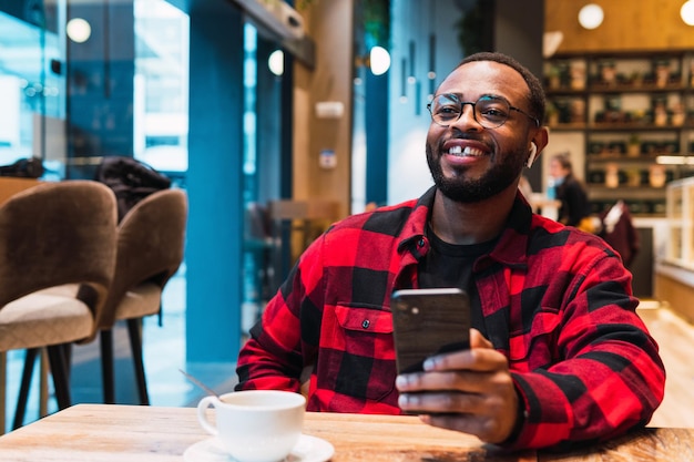 Vreemde zwarte man met smartphone in een café.