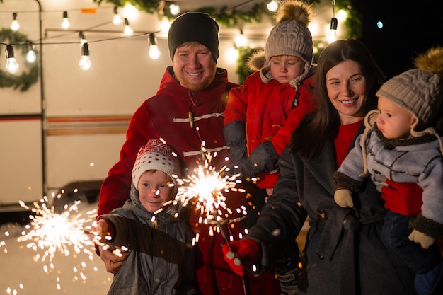 Foto vreugdevol gezin met een vonkel in de hand's nachts buiten
