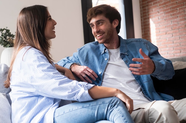 Vreugdevol millennial interraciale geliefden genieten van tijd samen thuis gelukkige Arabische man en Indiase vrouw zitten op de bank in de woonkamer omhelzen en hebben gesprek Liefde familie relatie