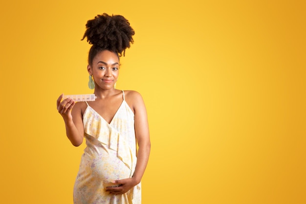 Vreugdevol millennial zwarte dame aanraken grote buik genieten van zwangerschap show vitamines pillen geïsoleerd op