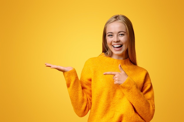 Vreugdevol tienermeisje demonstreert iets op haar lege handpalm